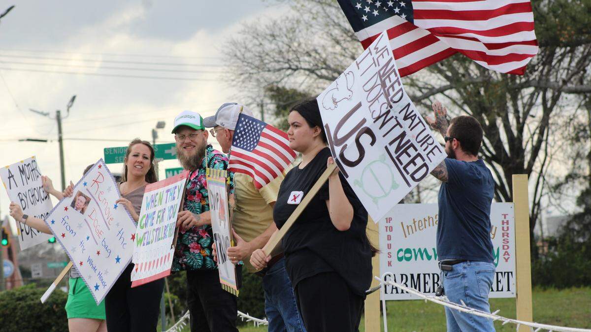 Six protesters opposing President Donald Trump assembled on Saturday, March 15, 2025, at Perkins Park in Warner Robins, Ga. Samantha Thurman, 16, organized the protest, wore a black shirt with a red X crossed over a swastika and waved a sign that said, “We need nature. It doesn’t need us.”