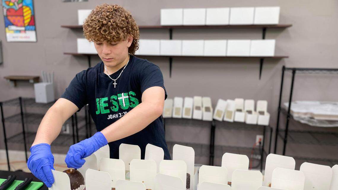 Eli Brown, son of Clayton and Cindy Brown, the new owners of The Apple Basket in Centerville, packages gourmet caramel apples for a customer at the shop’s reopening Monday, May 5, 2025.