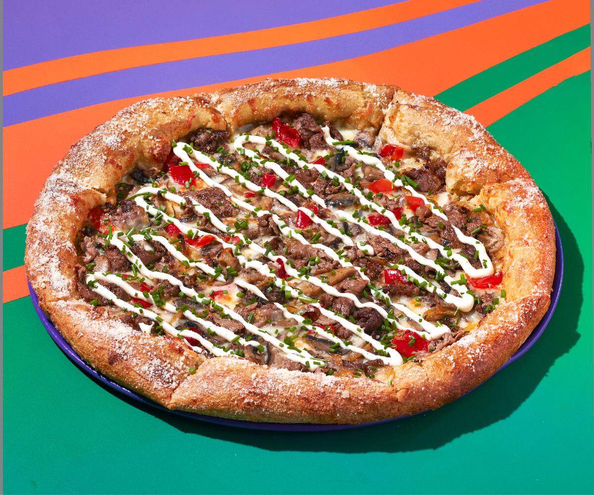 Limited-time-only steakhouse pizza at Mellow Mushroom in Warner Robins. An olive oil and garlic base topped with all-natural grilled ribeye steak, roasted shiitake, button and portobello mushrooms, creamy mozzarella, caramelized onions, spicy pickled peppers and then finished with chives and a garlic aioli drizzle. Available through May.