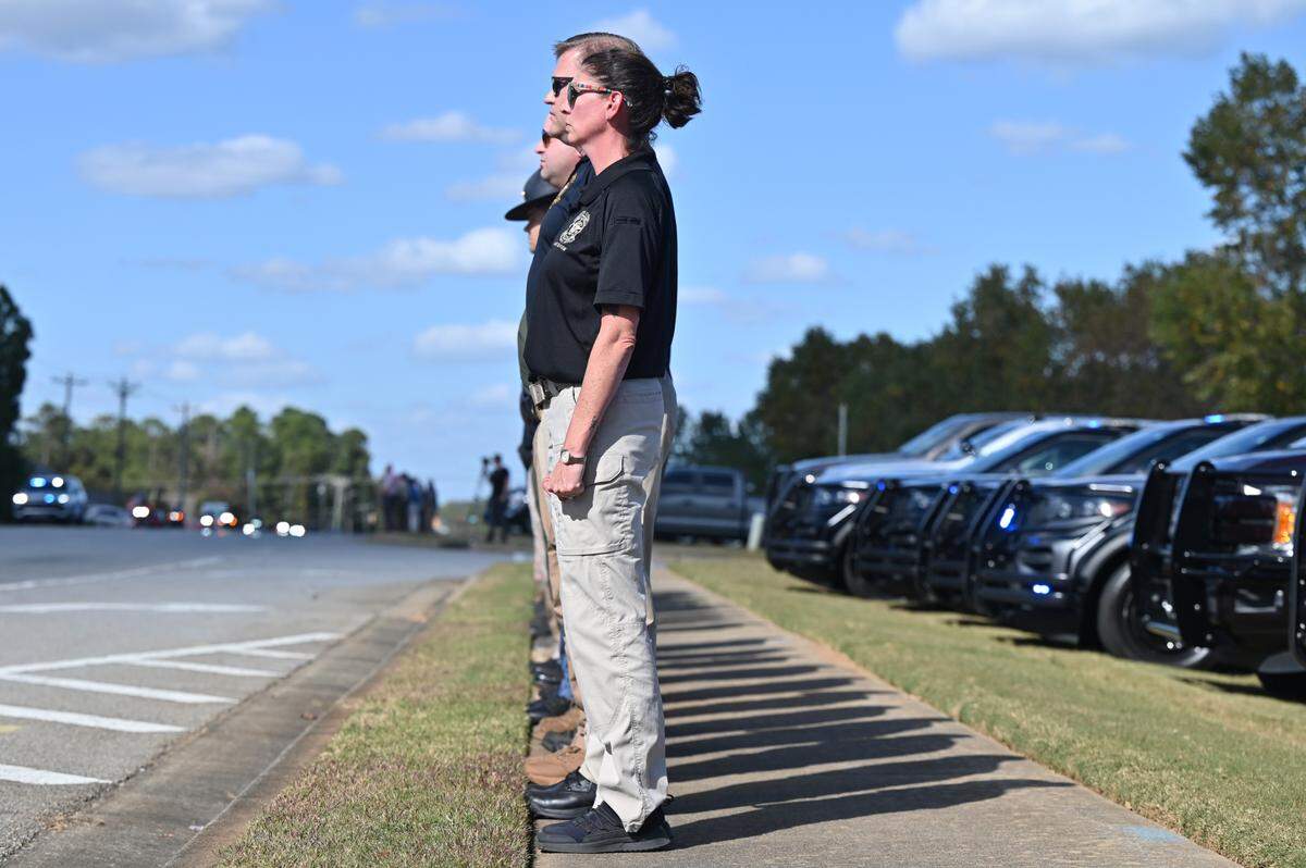 Members of the Houston County Sheriff’s Office stand at attention as a procession for the late Houston County Sheriff Cullen Talton on Tuesday, Oct. 22, 2024, outside of the Houston County Sheriff’s Department in Warner Robins, Georgia. Sheriff Talton died peacefully on Saturday at age 92 and served nearly 52 years as sheriff.