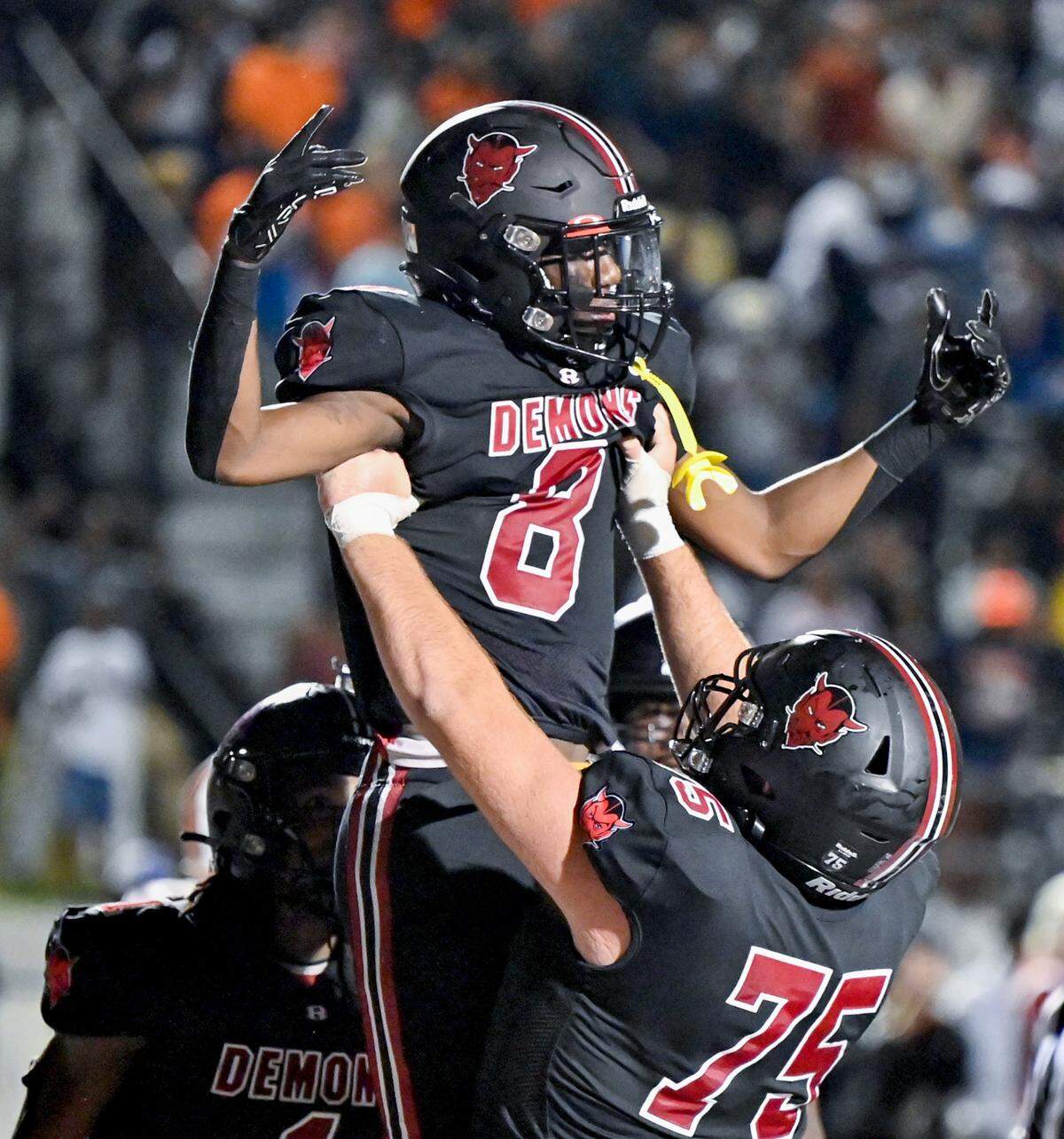 Warner Robins’ Jeremiah Jackson (8) gets lifted up by teammate Nick Reeves (75) after his game winning touchdown in the Demons’ 39-35 win Friday night over Northside.