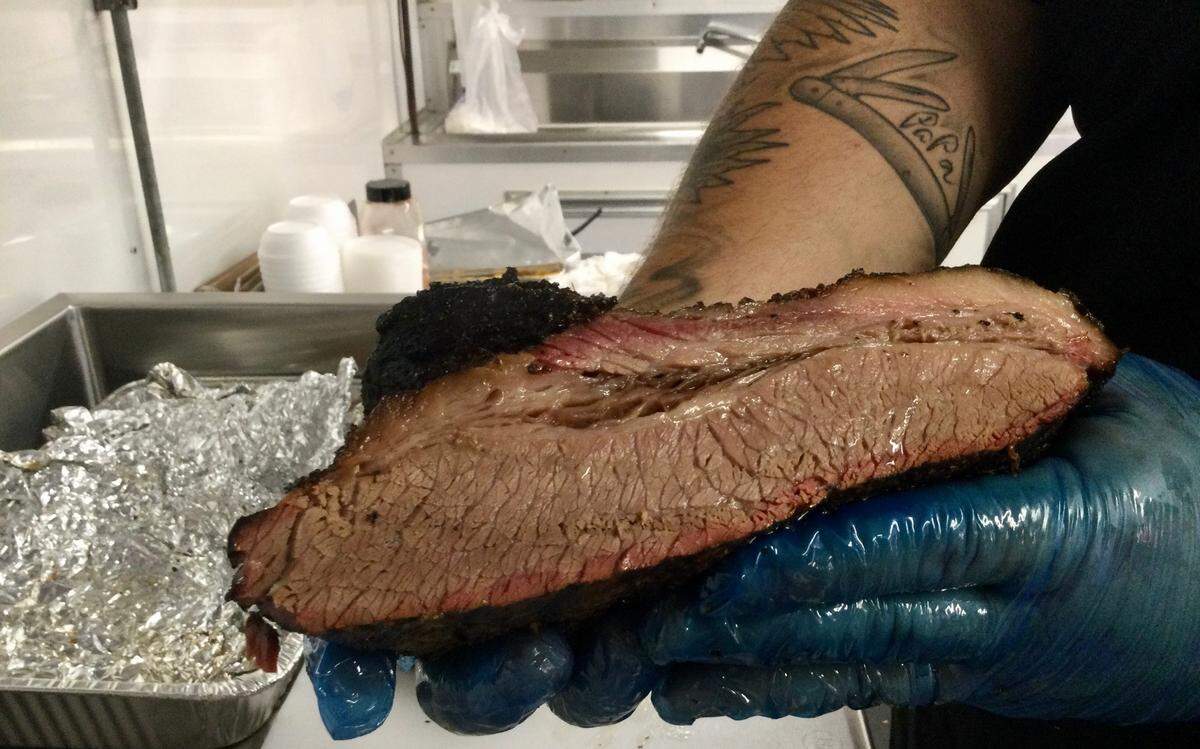 Matthew Martin, co-owner of Smoke South Craft BBQ and Catering, holds up a beef brisket that he’s smoked for 16 hours. He and his wife, Jesica, are carrying on the family tradition of Southern pit barbecue - something they learned by working at the popular Martin’s BBQ in Warner Robins that closed in late 2020.