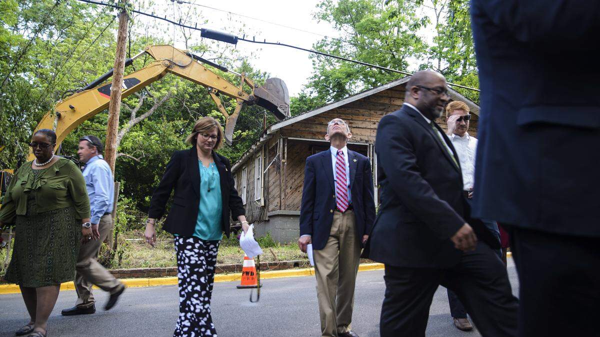 Officials move out of the way of an excavator before it begins tearing apart the home at 555 Cynthia Ave. in Macon in April. Macon-Bibb County celebrated the demolition of the 100th blighted home of the year April 23. The house at 555 Cynthia was the first of three up for demolition on the block, all of them within sight of Elam Alexander School on Second Street.