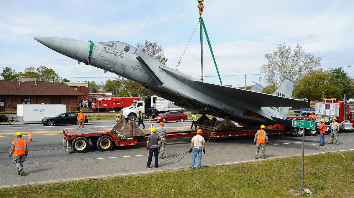An F-15 is set down on a flat-bed trailer on Ga. 247 Saturday. The plane has been on a pedestal at Robins Air Force Base for many years but is relocating to the Museum of Aviation.