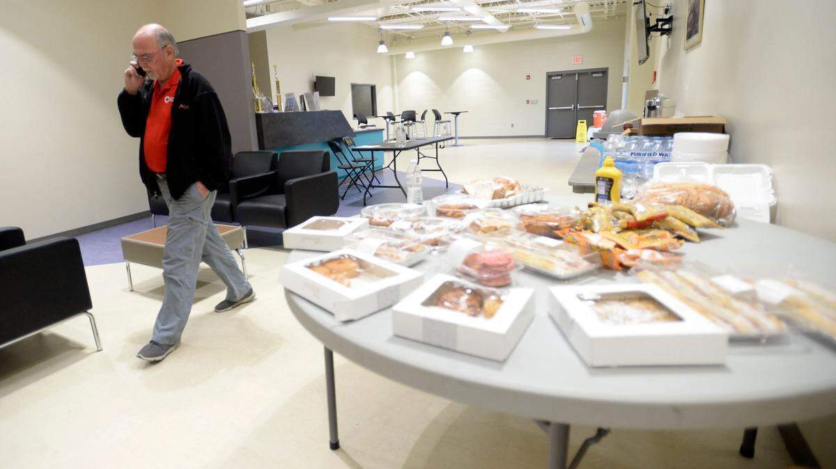 Red Cross mass care leader Stephen Pollitt, left, paces the Memorial Gym where donations of food were set for lunch Saturday for evacuees from Crystal Lake Apartments. After talking with EMA director Spencer Hawkins, Pollitt said he would be getting ready to serve a dinner meal from the Salvation Army and get cots ready to house residents displaced by the emergency.