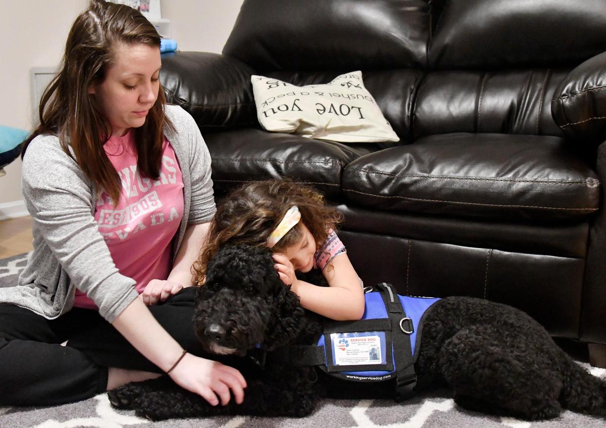 JASON VORHEES/THE TELEGRAPH Warner Robins, GA, 01/08/2020: Whitney Cochran looks down as her daughter Dylan, 5, hugs Benny, her diabetic alert dog at their home in Warner Robins January 8, 2020. Dylan was diagnosed with type 1 diabetes at age 3.