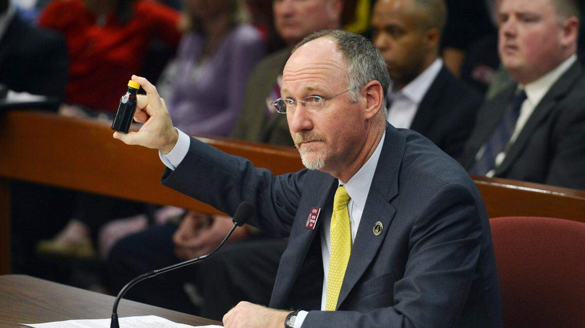 Former Rep. Allen Peake holds a vial of what cannabis oil looks like while appearing before the Georgia Legislature’s Health and Human Services Committee in 2014.