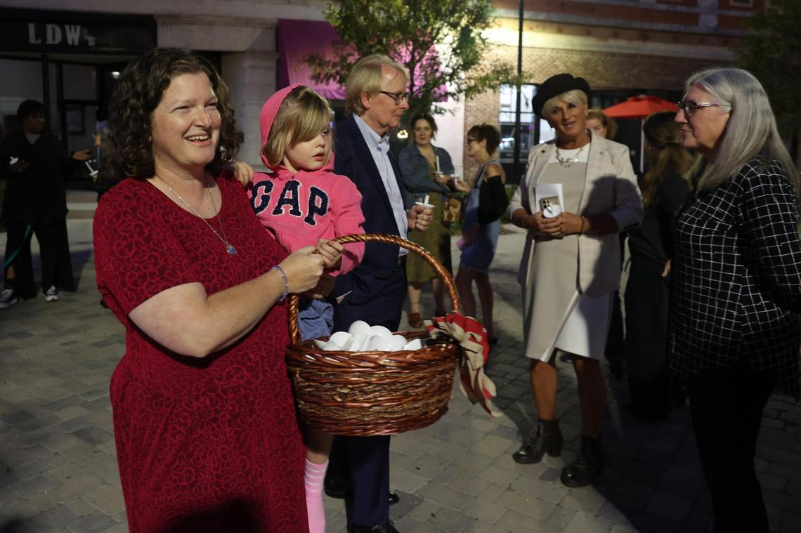 Centenary Church senior pastor Sara Pugh Montgomery carries her daughter Mille, 5, while passing out candles at the candlelight vigil on Cotton Avenue Plaza on Tuesday, Nov. 12, 2024, in downtown Macon, Georgia. Rather than honoring the life of someone who has passed, organizers said that the vigil was an opportunity for members of the LGBTQ+ community and allies to gather following the results of Election Day a week prior.