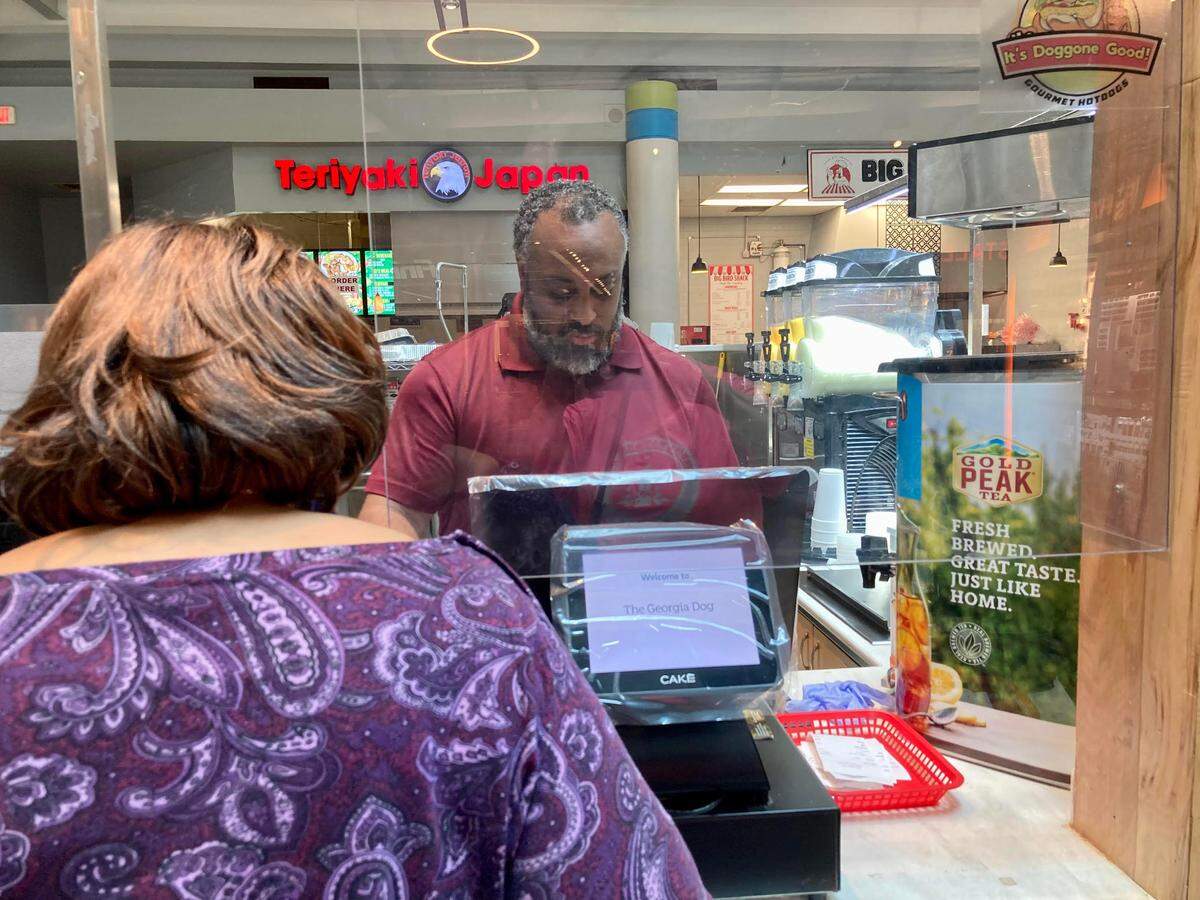 Gloria Battle of Macon pays for her gourmet hot dog at The Georgia Dog, a new walk-up restaurant inside the Houston County Galleria Mall in Centerville. LC Ashford, (right), along with his wife, Rebecca, owns The Georgia Dog.