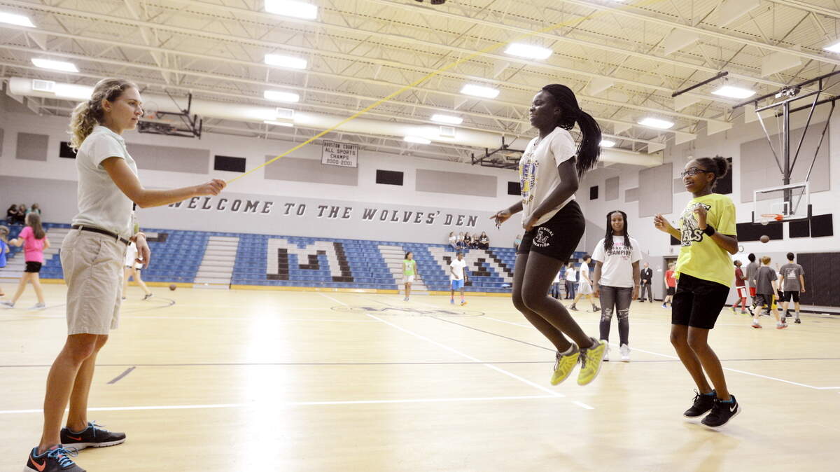 Substitute teacher Ashley Cortez helps eighth-grade students at Feagin Mill Middle School in a game of jump rope.