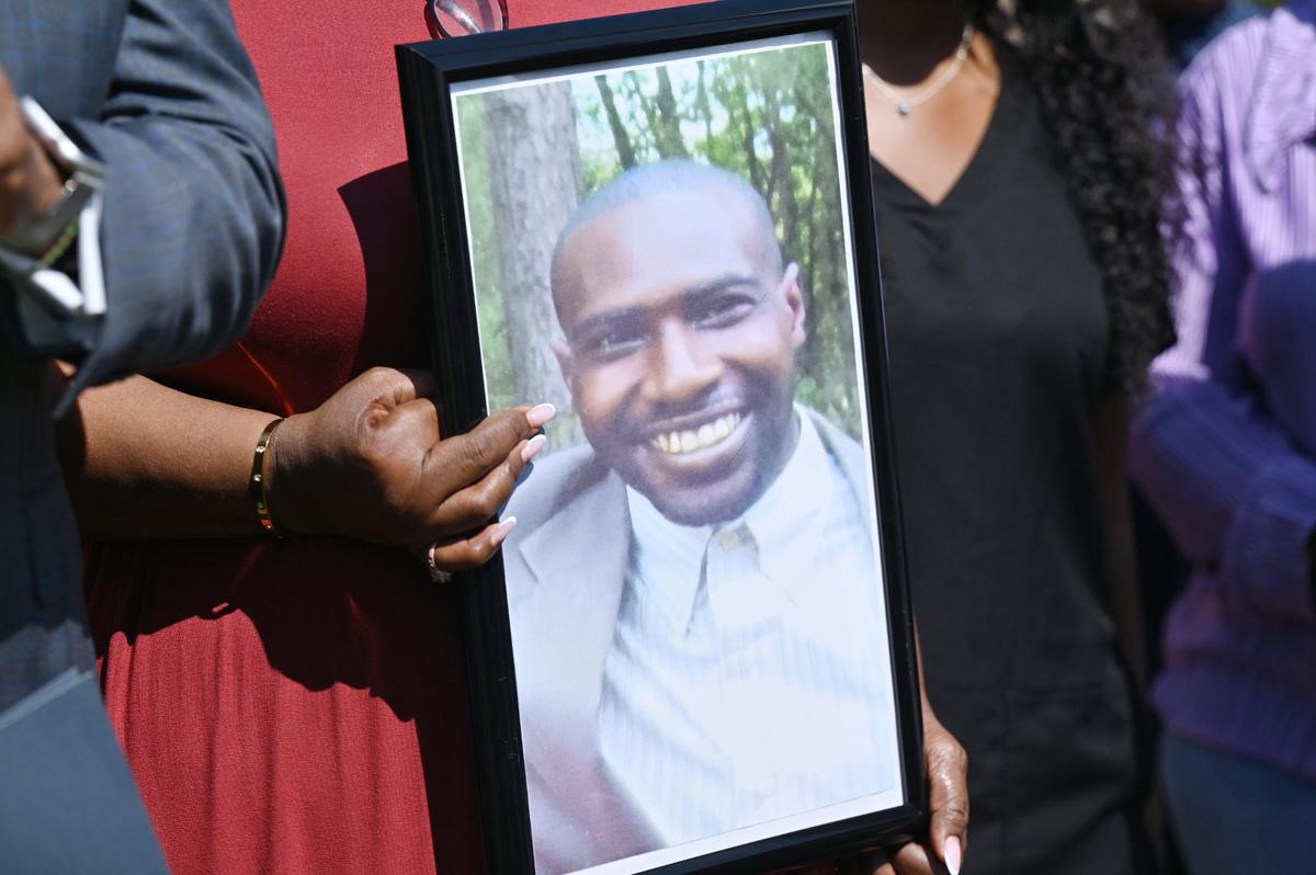 Paula Platt holds a photograph of her son Stephen Fossett during a press conference discussing his death on Wednesday, Aug. 28, 2024, outside of the Bibb County Jail in Macon, Georgia. Fossett died in late May while in custody at the Bibb County Jail after experiencing a medical emergency and subsequent tasing, his family says.