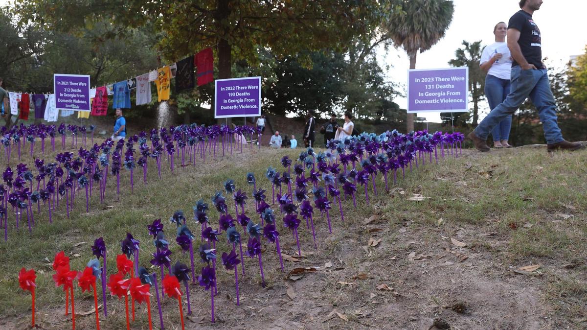 A vigil attendee walks by the pinwheel project as a part of the Domestic Violence Awareness Month candlelight vigil in Washington Square Park on Tuesday, Oct. 29, 2024, in Macon, Georgia. Each pinwheel represents one death from domestic violence in Georgia and the red pinwheels represent deaths in Middle Georgia.