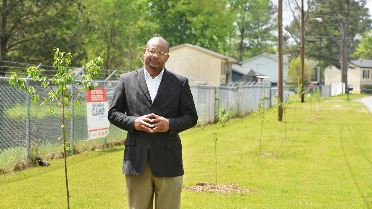 Frank Austin stands in front of the 30 cherry trees planted in Village Green, where the work to reverse blight is ongoging, in this April 2015 photo.