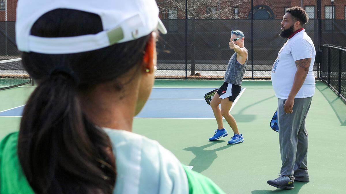 Pickleball Instructor Angie Coggins (middle) gives a thumbs up to teacher Courtney Hickey at Tattnall Square Park Wednesday morning during a learning day for Bibb County teachers. Middle school, high school and elementary school PE teachers took lessons on how to play and keep score of the game.