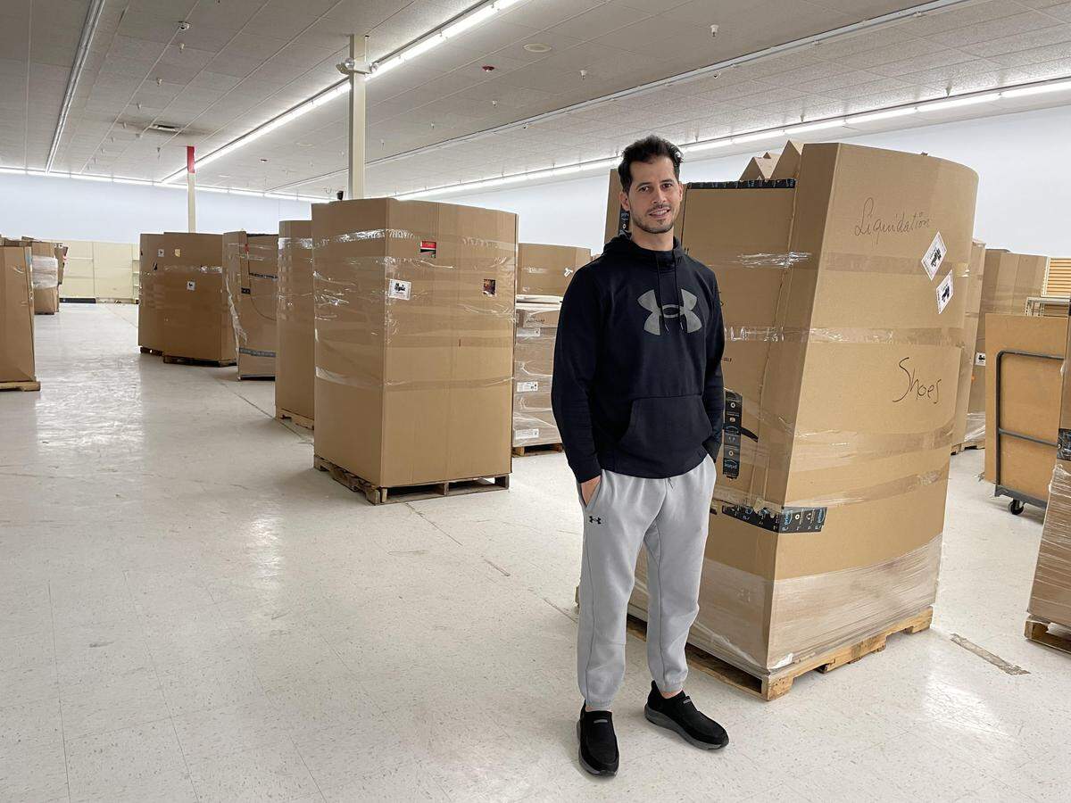 Salem Okasha, co-owner of Deals Outlet, stands in the distribution area of the new Warner Robins location amid boxes of unpacked inventory.