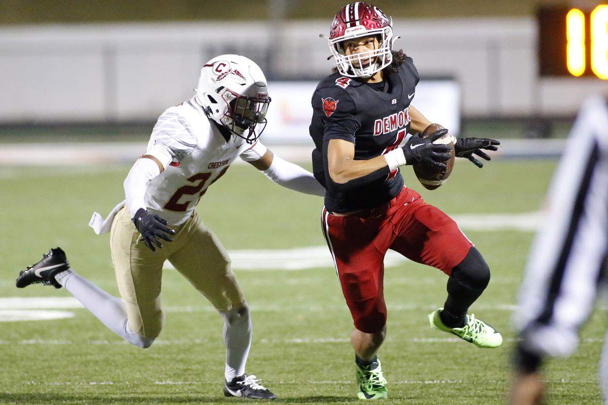 Warner Robins’ Isiah Canion eludes a defender after a 7-yard catch Friday night during the Demons’ quarterfinal playoff game against Creekside.