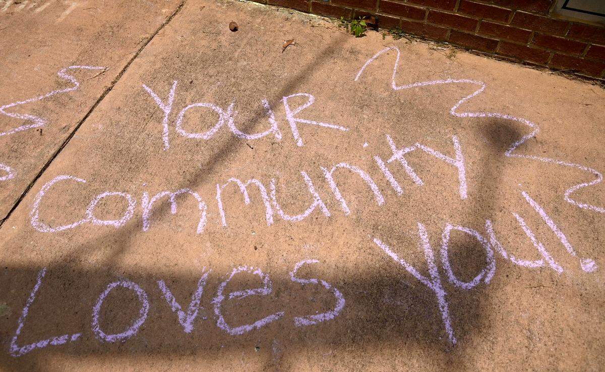 A chalk drawing reads “Your Communty Loves You” across from Temple Beath Israel as hundreds of people gather at for a counter-protest Saturday afternoon after an antisemitic hate group gathered outside the Temple Friday.