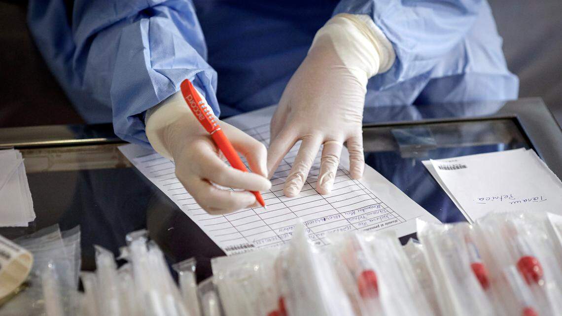 A health official prepares to take samples for a coronavirus test from a journalist in Bucharest, Romania.