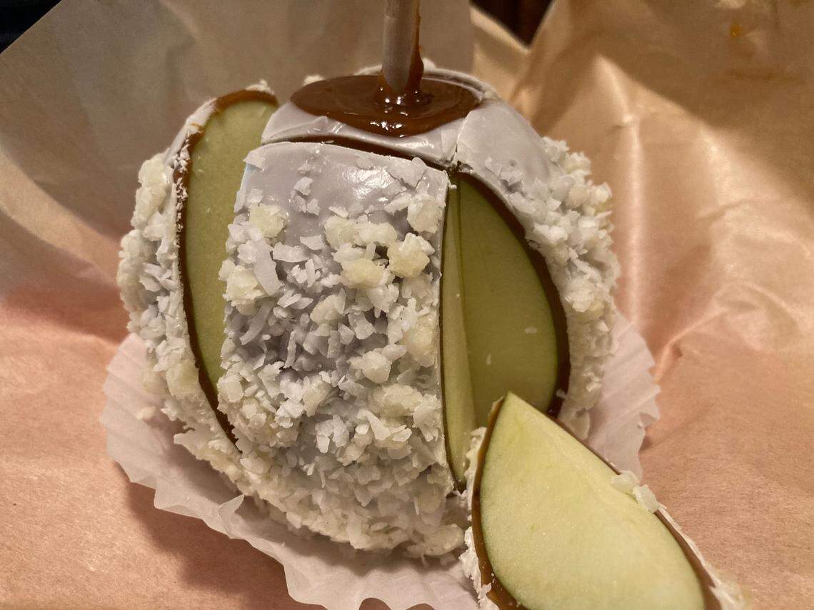 A pina colada gourmet caramel apple sliced and ready to eat from The Apple Basket in Centerville. The shop reopened Monday under new ownership, May 5, 2025.