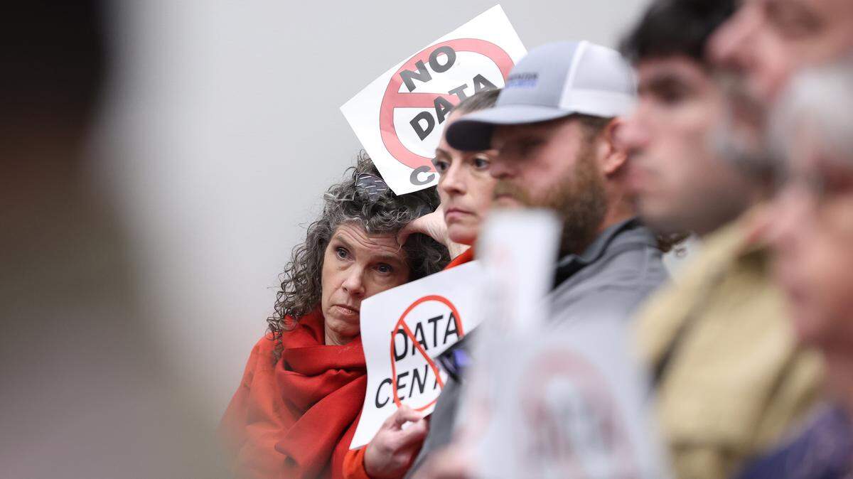 Michelle Tollison (left), from Forsyth, holds a “No Data Center” sign while listening to public comment in favor of the rezoning request for land for a proposed data center on Monday, Feb. 2, 2026, at Forsyth City Hall in Forsyth, Georgia. Forsyth city council voted unanimously to rezone part of the site back to agricultural land and voted 5-1 to approve a conditional use application, which allows data centers in agricultural zones and will move the Johnstonville Road data center project forward. 