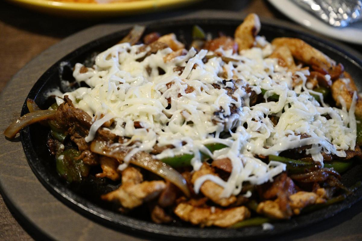 Alambres Fajitas sit on a table inside of Cozumel Mexican Grill on Wednesday, April 23, 2025, in Perry, Georgia. The dish includes grilled steak and chicken, with peppers, onions, bacon and cheese.