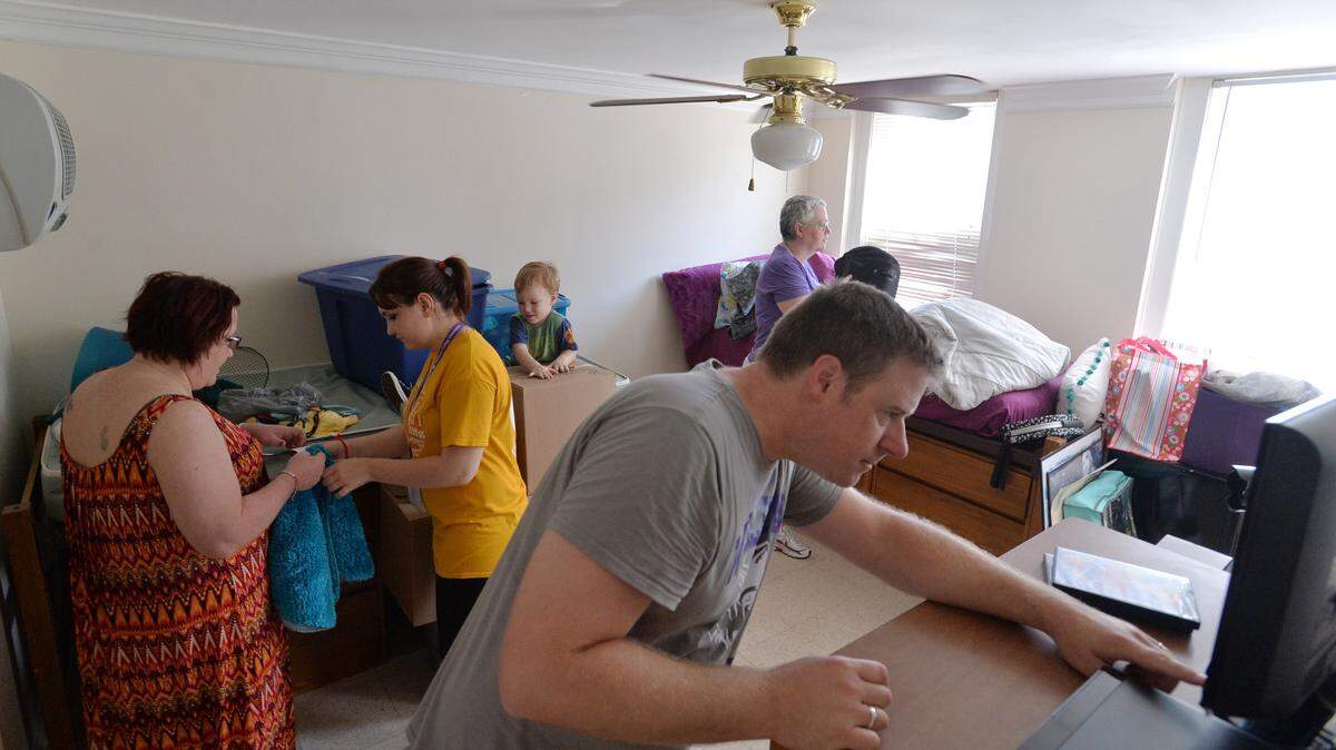 John Stiles-Williams, right, sets up a DVD player for his daughter, Grace, and her roommate, Tara Reigel, while her family unpacks stuff for their Wesleyan College dorm room.