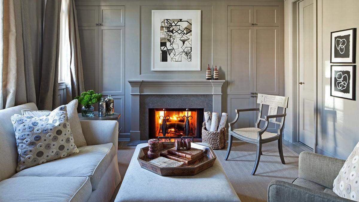 RON BLUNT /FOR THE WASHINGTON POSTA fire crackles in a gray family room in a Washington townhouse designed by Mary Douglas Drysdale.