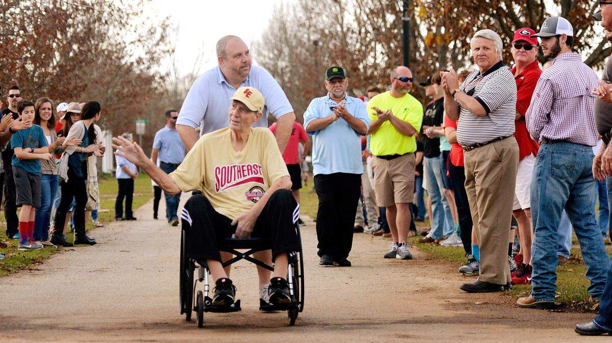 Tommy Morris acknowledges the crowd gathered to honor him as he is wheeled into the Warner Robins American Little League complex by his son Brad Morris on Dec. 27.
