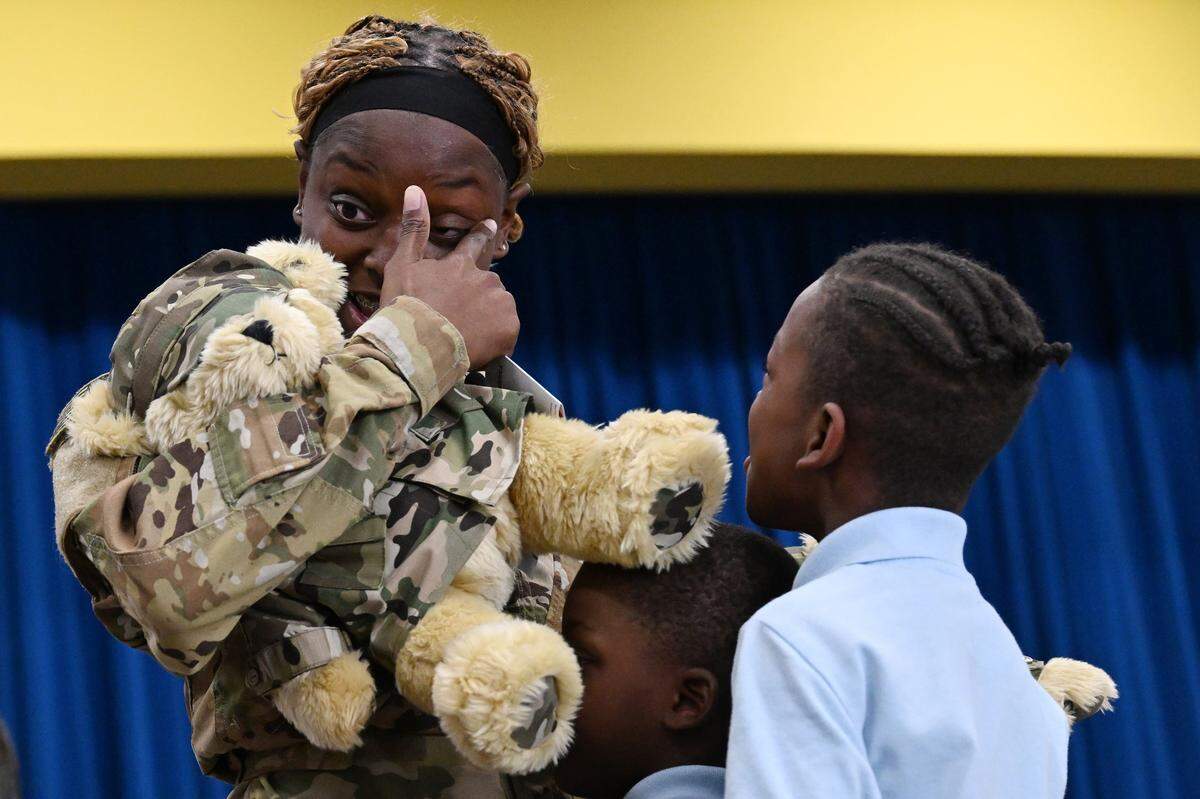 U.S. Army Sgt. Shanterria Rocker wipes her eyes after reuniting with her sons Josiah (right) and Jaxon on Friday, Nov. 21, 2025, at John R. Lewis Elementary School in Macon, Georgia. Rocker returned from a nine-month deployment in Poland to surprise her two sons on Friday. 