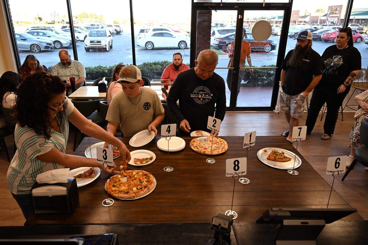 Friends and family of staff members sample different Indian-Italian fusion pizzas ahead of the three-day grand opening Friday, Oct. 17, 2025, of the new Slice and Spice restaurant in Warner Robins, Georgia.