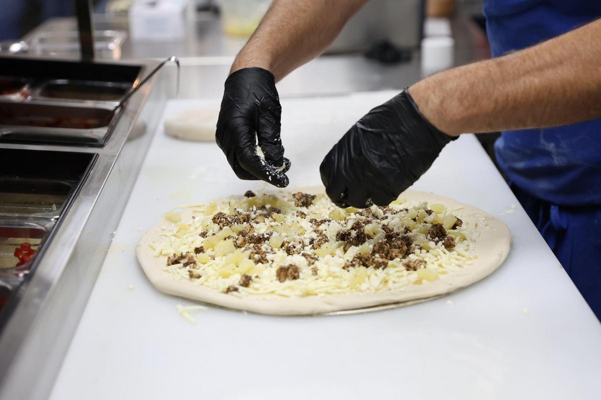 Amici kitchen manager Branden Hudson sprinkles cheese on a Pineapple Express pizza during staff training on Wednesday, Oct. 16, 2024, in Perry, Georgia. The new Perry location of Amici is set to open to the public on Monday and will be Perry’s first brewery.