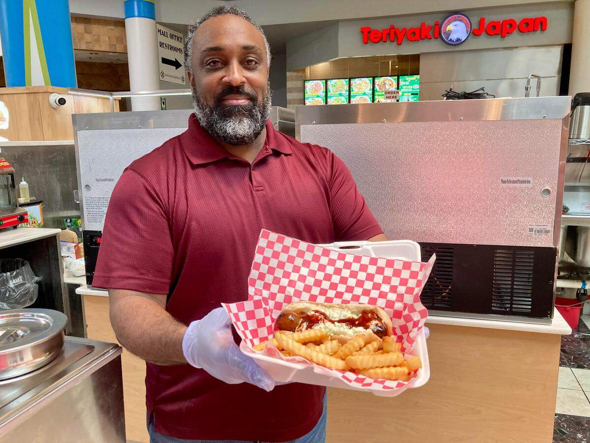 LC Ashford serves up a sausage dog topped with coleslaw and a spicy BBQ sauce with a side order of fries at The Georgia Dog, a new walk-up restaurant inside the Houston County Galleria in Centerville.