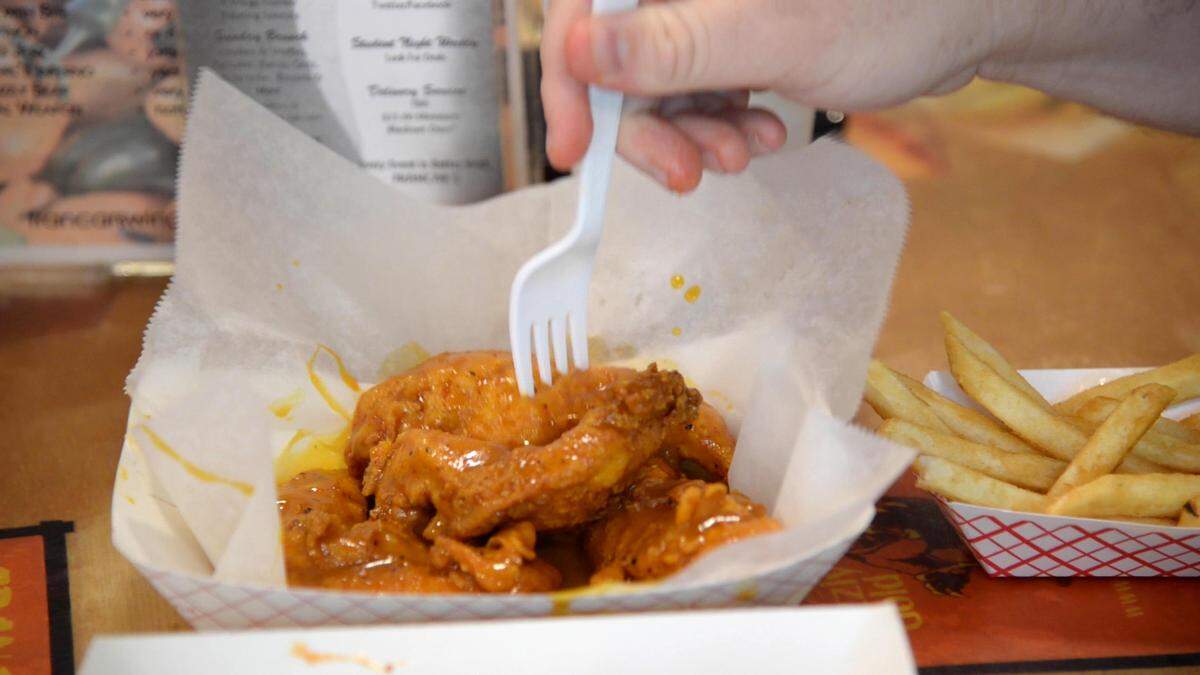 JENNA EASON/THE TELEGRAPH Macon, GA, 06/18/2019: Reporter Justin Baxley sticks his fork into a chicken strip covered in Mercer Gold sauce at Francar’s Buffalo Wings for #FoodieFriday.