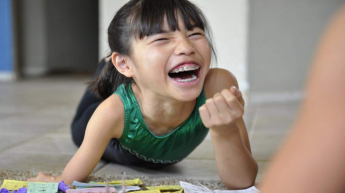Bethany Wong, 10, who was born with a deformed right arm, lets loose with a laugh as she plays a board game with sister Bayley. 