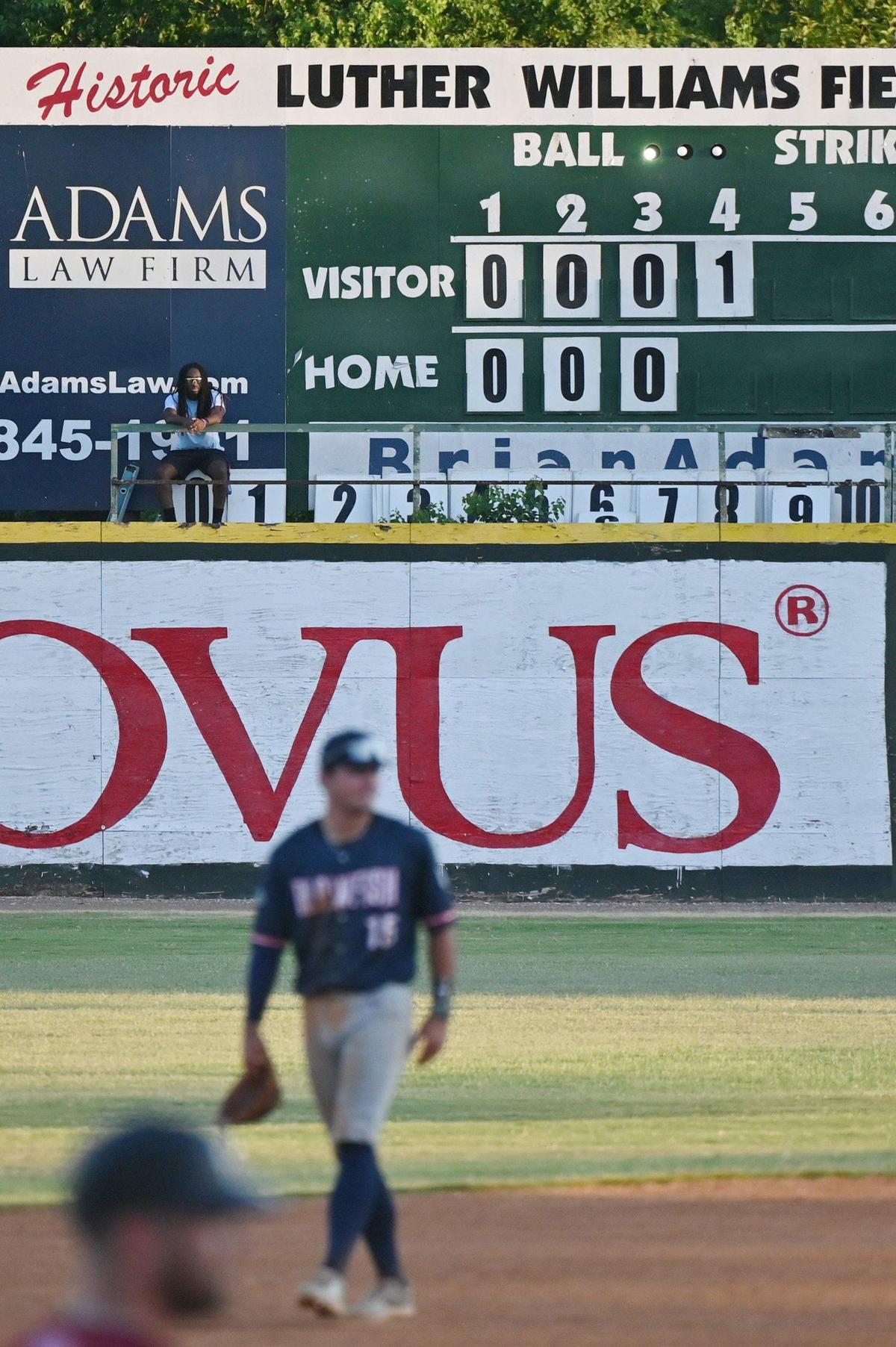 Luther Williams Field scoreboard operator Christian Kendrick sits up on the elevated manual scoreboard during the Macon Bacon game against Catawba Valley Stars on Tuesday, June 25, 2024, in Macon, Georgia. Luther Williams Field saw extensive renovations in 2018, but the scoreboard remains the original from the park’s opening in 1929.