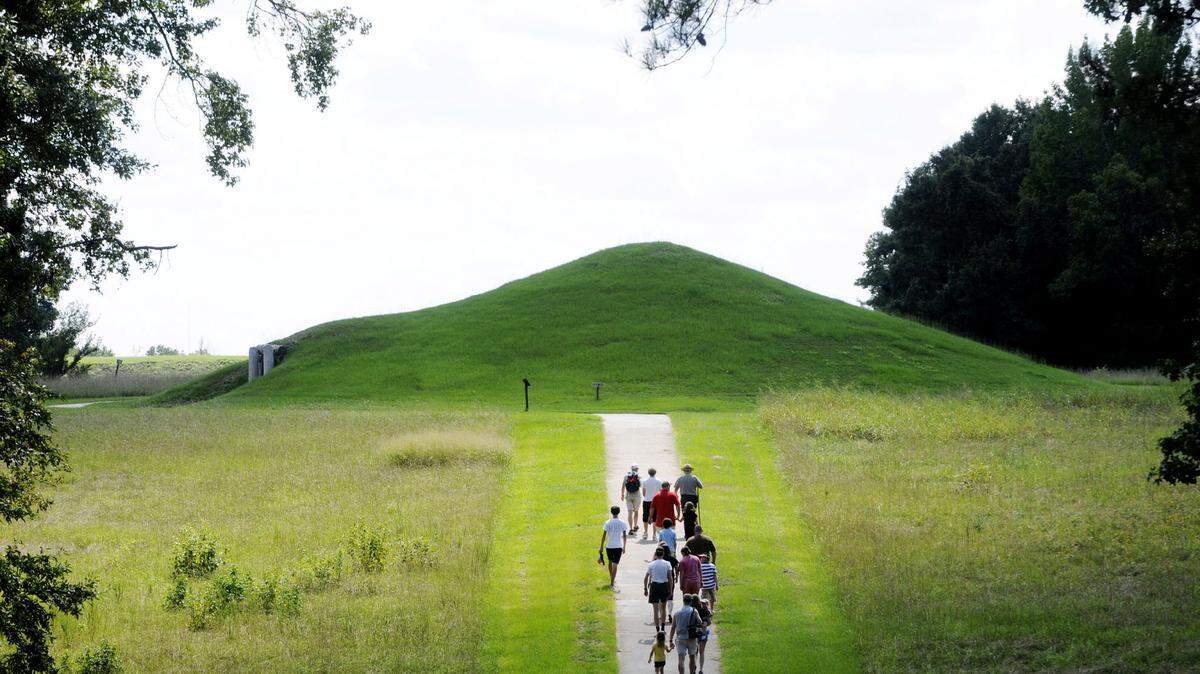 A ranger leads a tour group up the path to the Earth Lodge at the Ocmulgee National Monument.