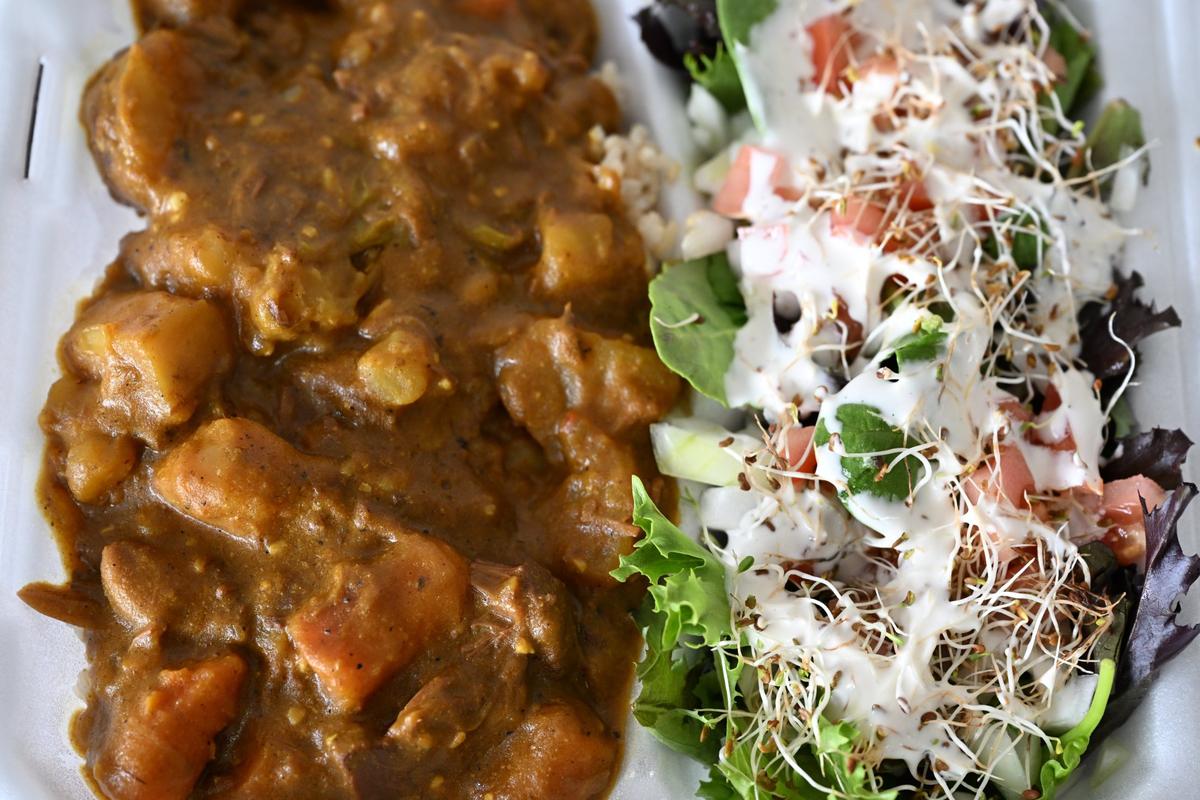 The Curry Jackfruit Stew served with a side salad sits on a plate inside of Verus Vine Plant-Based Kitchen on Tuesday, June 3, 2025, in Byron, Georgia. Verus Vine, which opened in May, features all plant-based recipes.