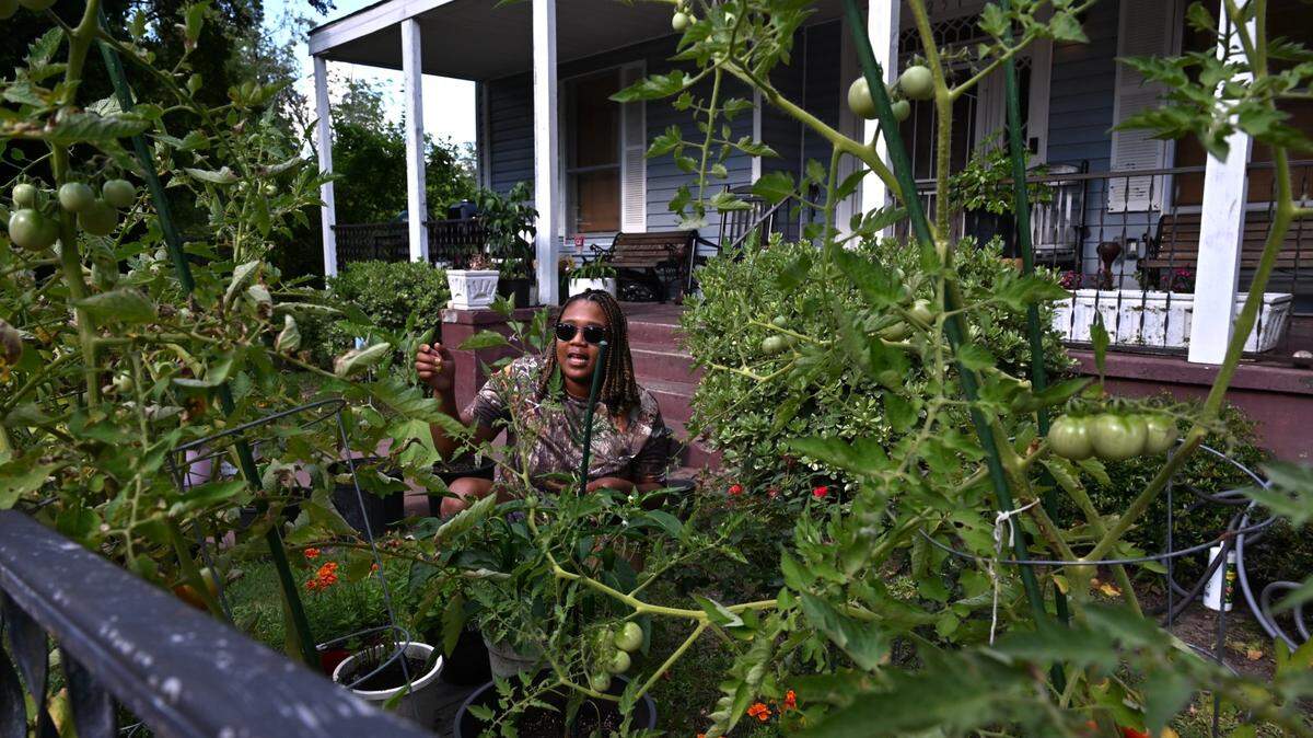 Andrea Moses, 36, sits in her front yard garden on Wednesday, July 2, 2025, on Ward Street in the Pleasant Hill neighborhood of Macon-Bibb County, Ga. Moses grows a variety of herbs and vegetables to eat including eggplants, tomatoes, bell peppers, habaneros, squash and basil.