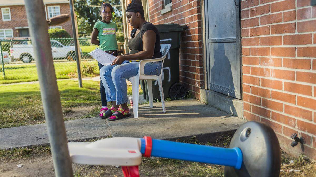 Lashonda Hill helps her daughter with her homework outside their apartment in the Tindall Heights public housing project. Hill is among those in the neighborhood who hope that the impending demolition and renovation of Tindall Heights will offer a shot at better schools for their kids.
