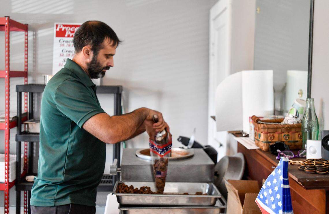 Tim Williams, owner the Nut House Pecan Company at 106 Main St. in Byron, bags praline pecans.