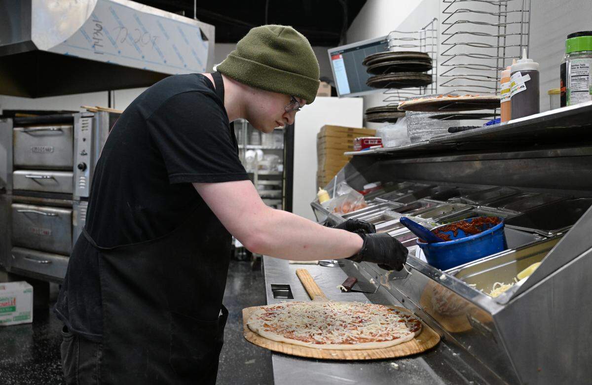 Home Slice Pizza employee Joseph Broussard adds cheese while making “The Home Slice” pizza on Tuesday, Aug. 26, 2025, in downtown Perry, Georgia. 