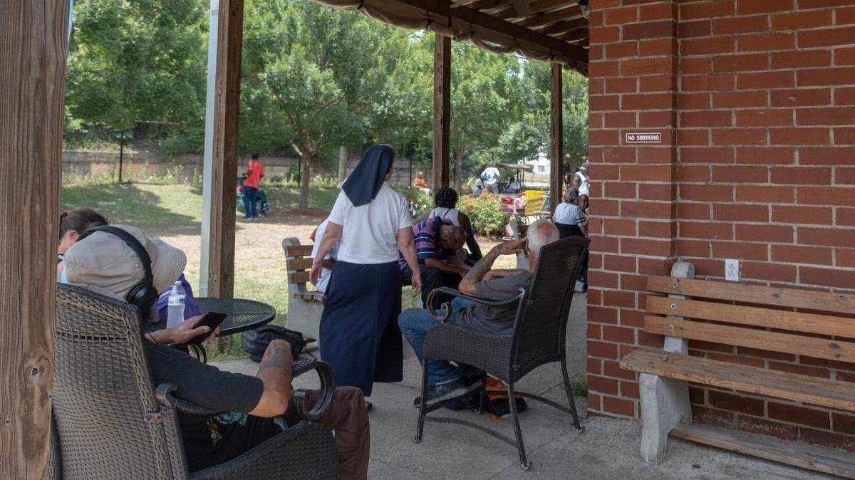 People seek relief in the shade outside the Daybreak Day Resource Center in Macon during snack time as temperatures in central Georgia reach close to 100 degrees.