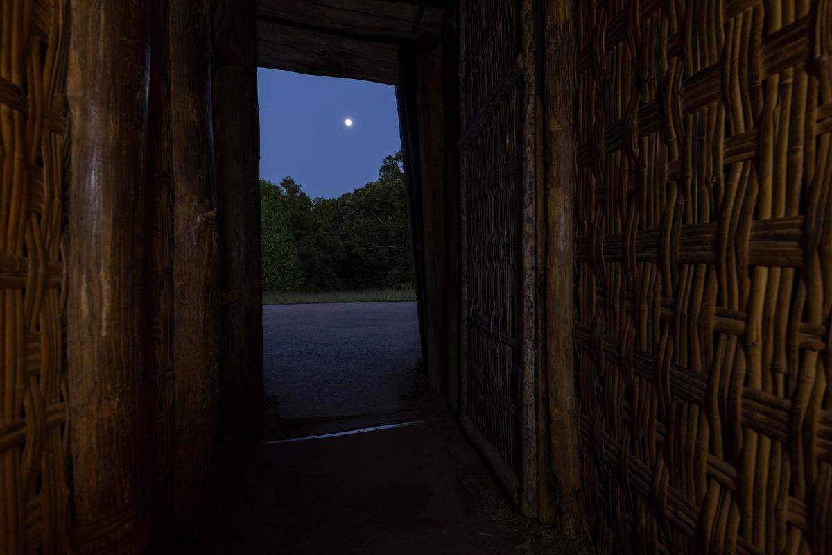 A full moon rises through the doorway of the Earth Lodge in the Ocmulgee Mounds National Historical Park.