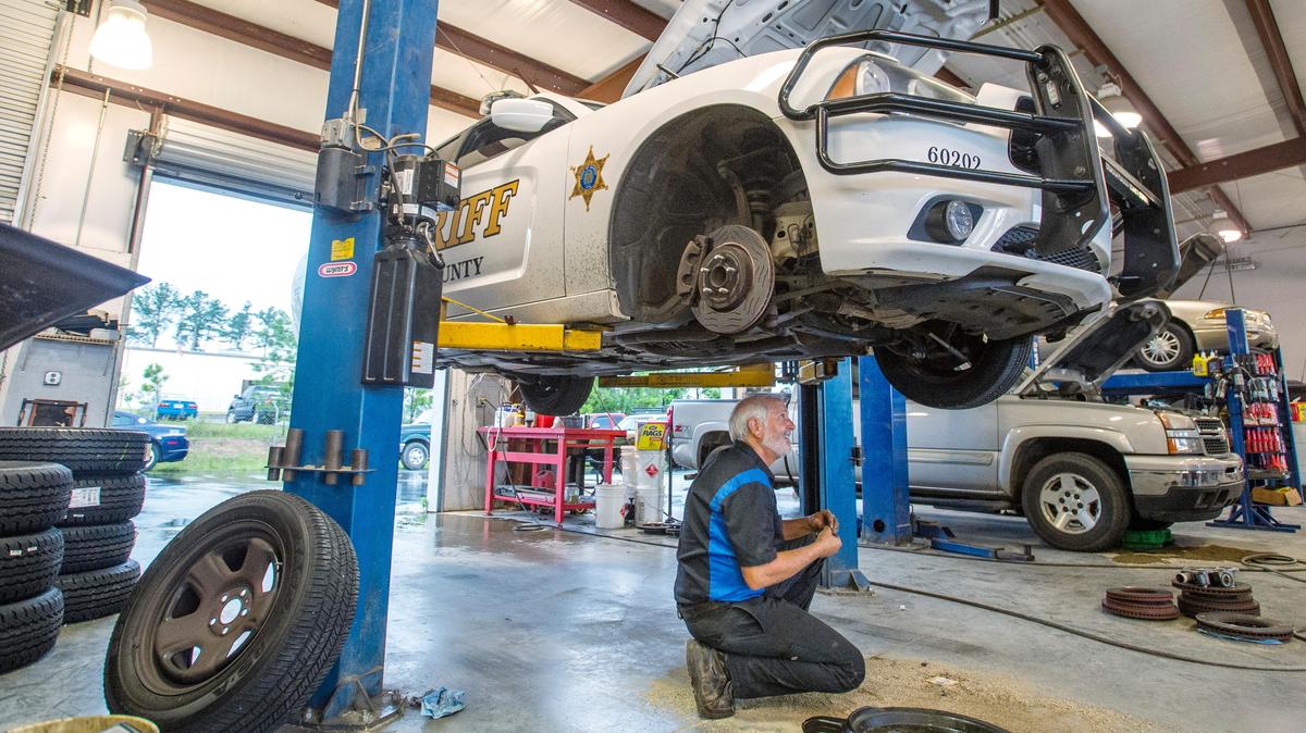 Jay Sears looks under a Bibb County sheriff's car on June 28 after installing a new power steering pump at Mitchell's Automotive.