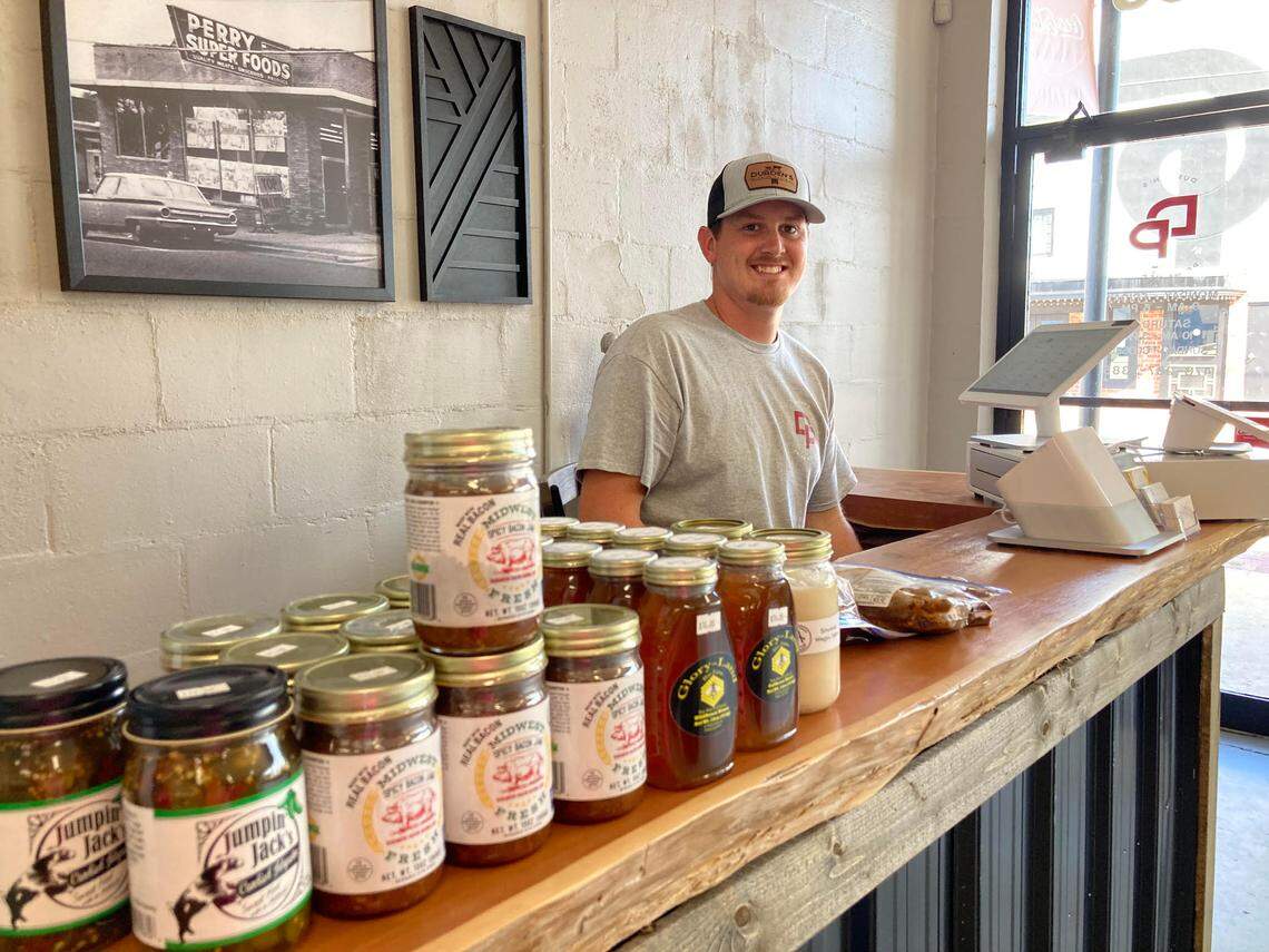 Cody Durden, who owns Durden’s Prime Meats in downtown Perry with is wife, Kallie, behind the register.