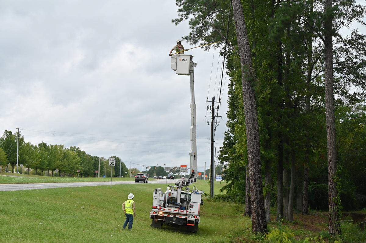 Georgia Power linemen work on removing a tree branch from a power line on Riverside Drive on Friday, Sept. 27, 2024, in Macon, Georgia. Multiple traffic lights and businesses down Riverside Drive are without power as of noon on Friday.