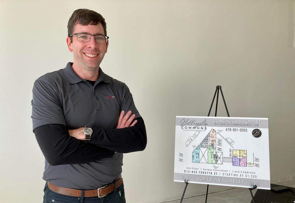 NewTown Macon’s executive director and CEO Josh Rogers stands next to a rendering showing commercial space at the new Billingslea Commons. Rogers died Sunday evening.