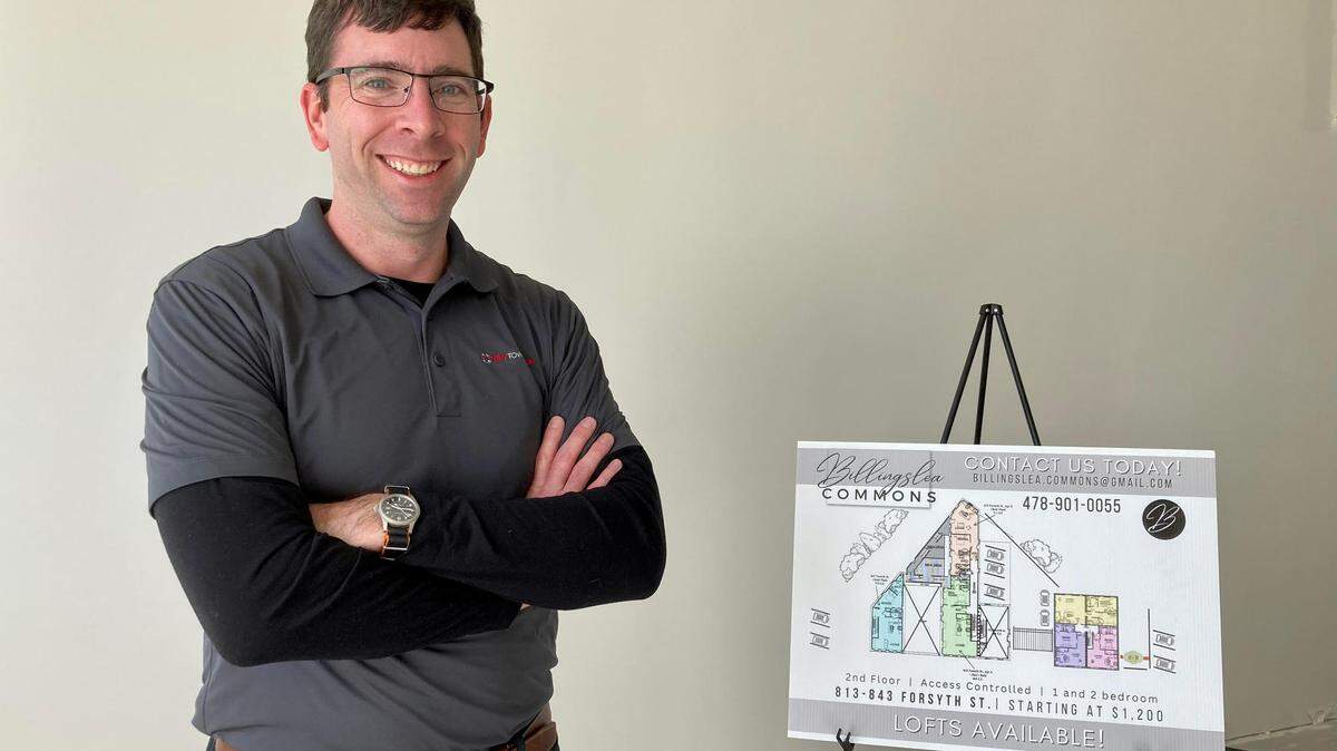 NewTown Macon’s late executive director and CEO, Josh Rogers, stands next to a rendering showing commercial space at the new Billingslea Commons in 2022. 