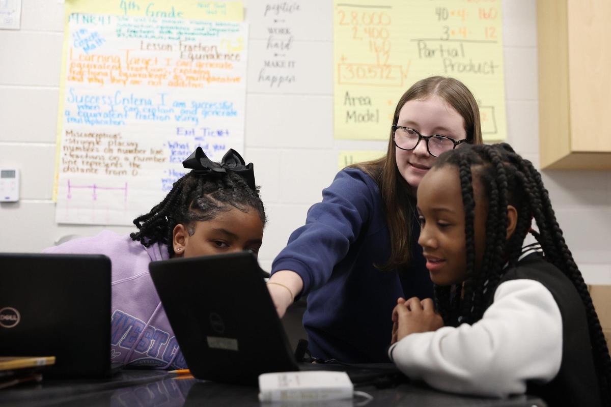Hutchings Academy student Jordan Pearson (middle) helps two students with an assignment in Montarrio Carter’s class at Ingram Pye Elementary School on Monday, Feb. 24, 2025, in Macon, Georgia. Pearson is one of a number of students in Hutchings “Teaching as a Career” pathway that prepares high school students interested in teaching as well as fills the state’s teacher employee gaps.