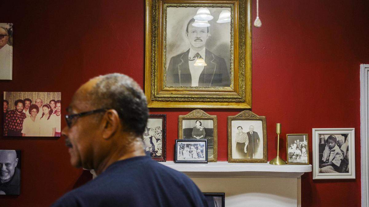 Mark Smith stands among photos of generations of his family in the home he grew up in in Hancock County. The house now belongs to his brother, Blaine, and is on one of the pieces of property the Sandersville Railroad wants a piece of for a short-line railroad.
